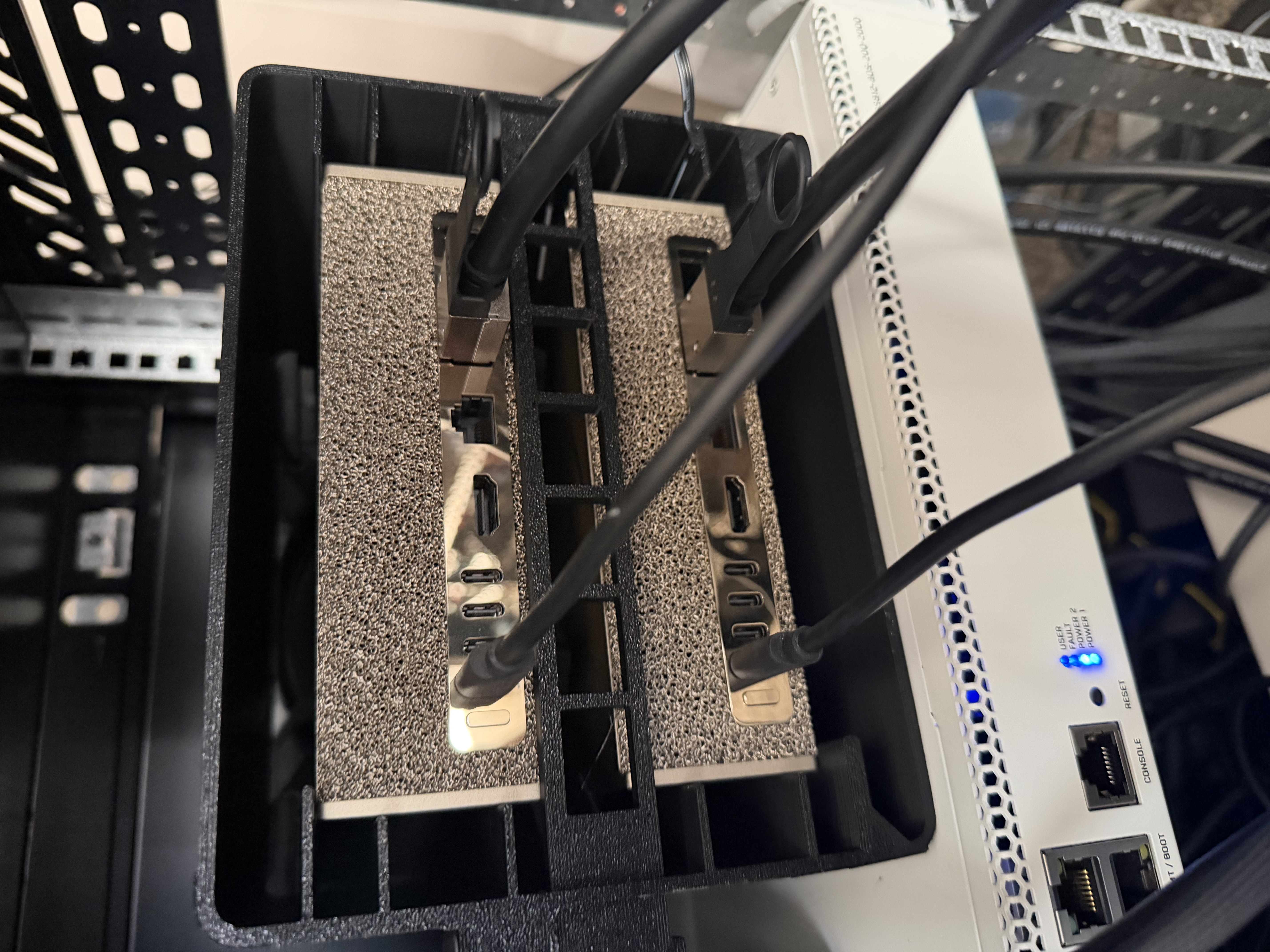 Rear of a black case containing two horizontally stacked Sparks, with side supports, connected cables, and a windowed retaining bar between the computers.